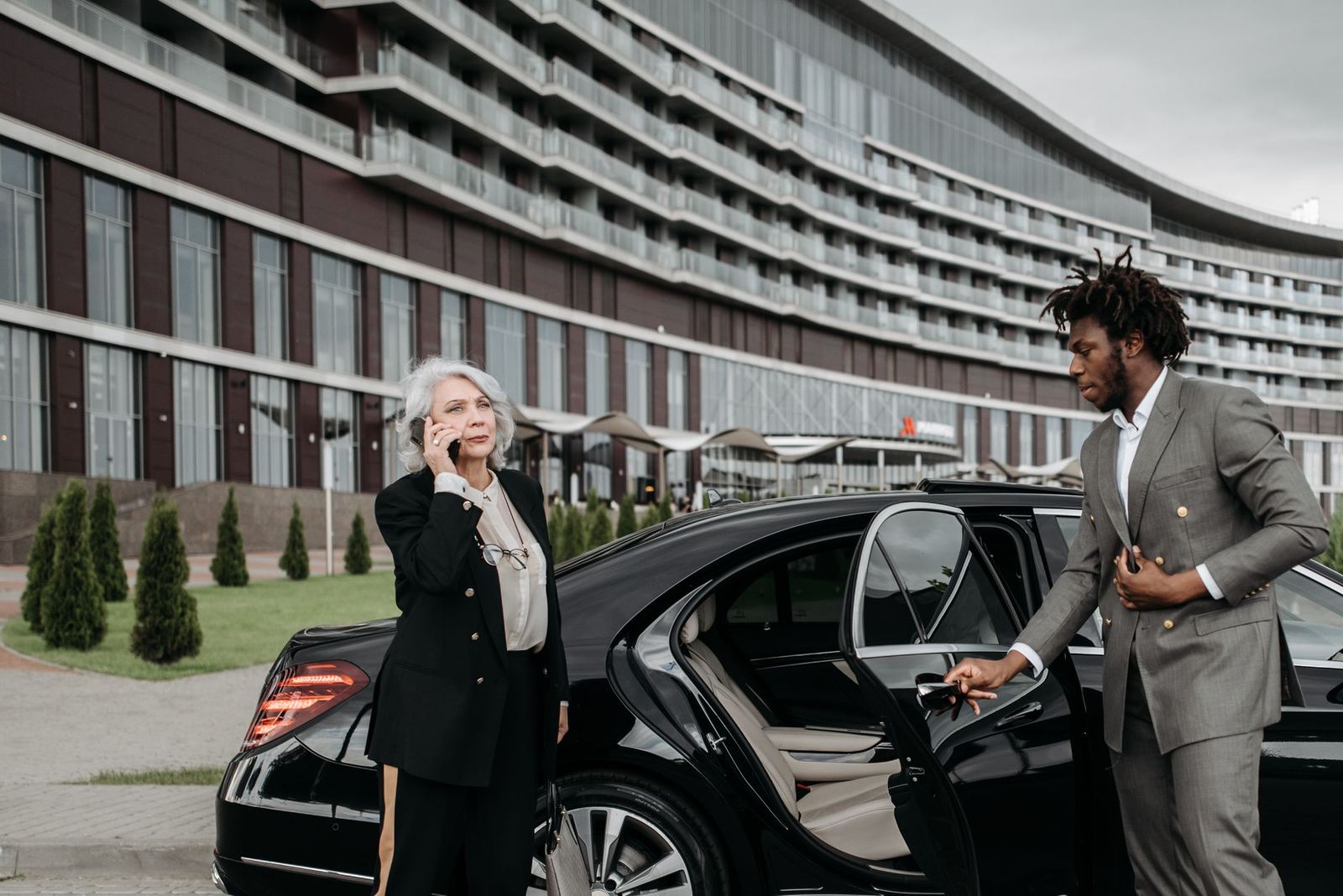 A chauffeur holding a car door open for an executive