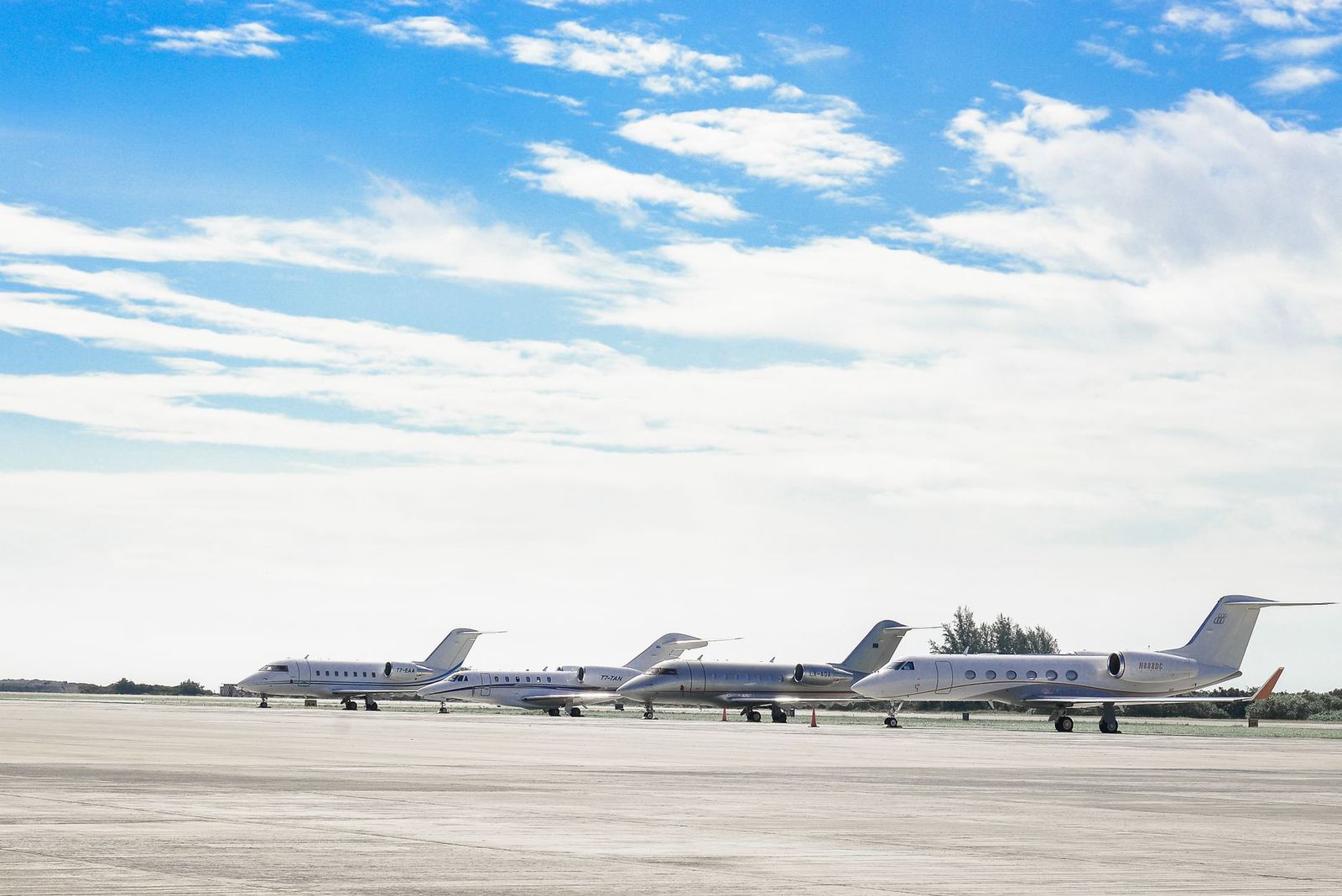 Private jets parked on an airport ramp under a clear sky