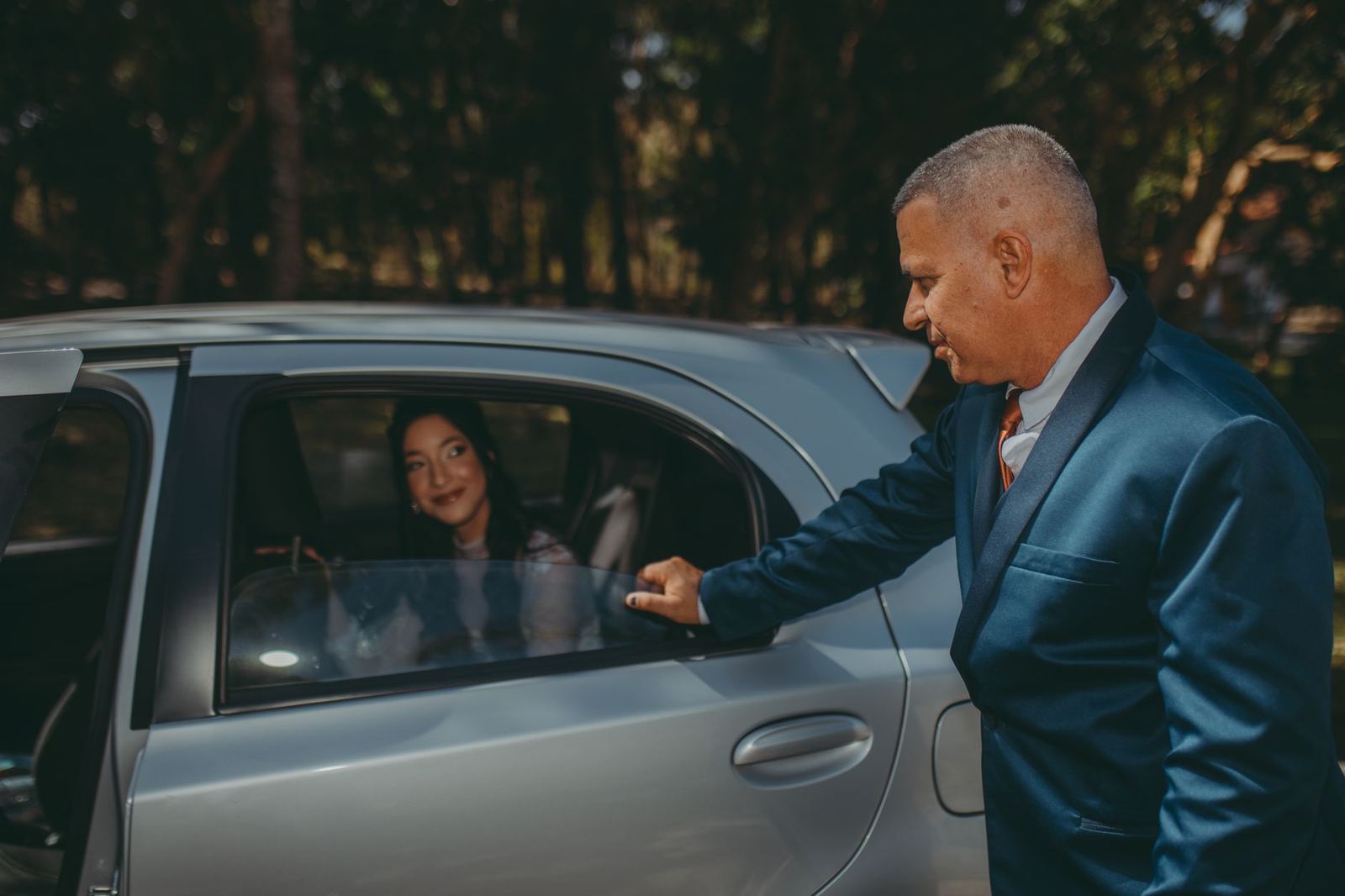 A chauffeur attending to a passenger in the rear of a car